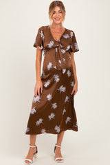 woman wearing a brown floral maternity dress with a tie front and short sleeves, showcasing her baby bump