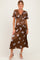 woman wearing a brown floral maternity dress with a tie front and short sleeves, showcasing her baby bump