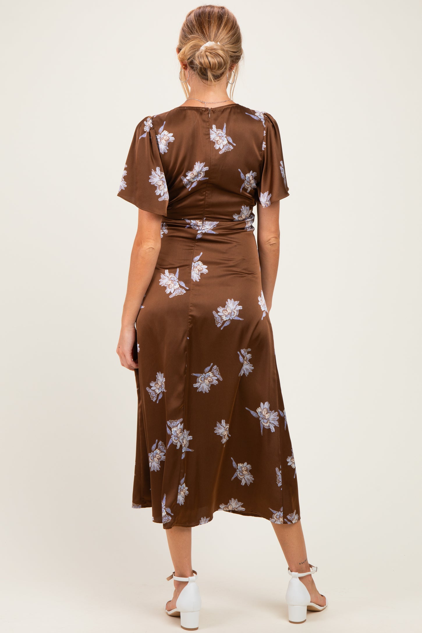 woman wearing a brown floral maternity dress with short sleeves and a flowy hem, showing the back view