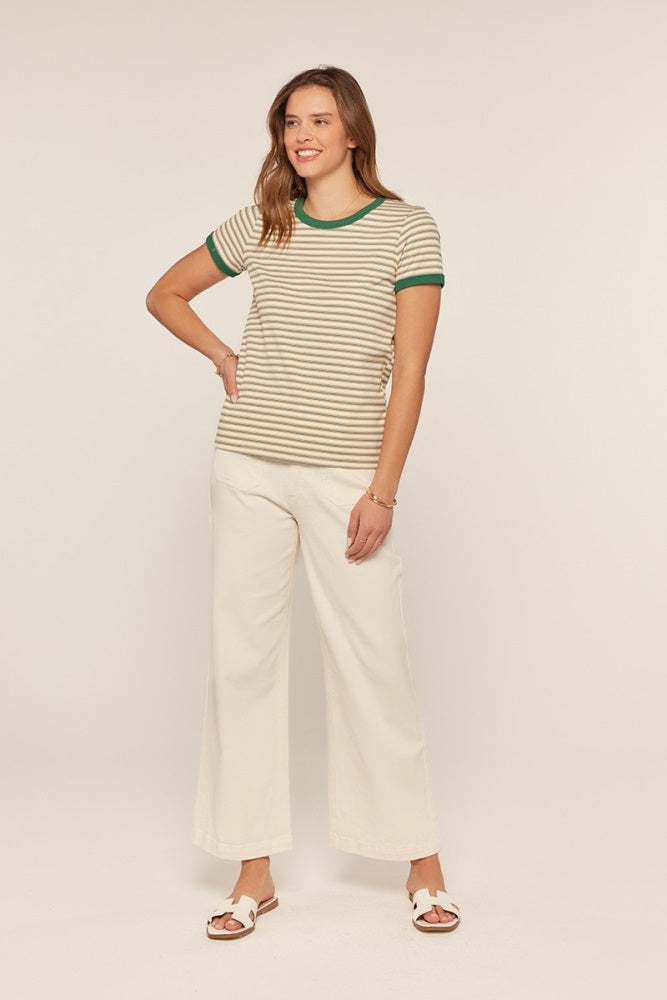 woman wearing a beige and olive green striped t-shirt with green trim and white wide-leg pants