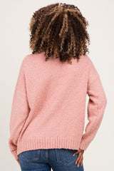 woman wearing a pink fuzzy maternity sweater, showing the back view, paired with blue jeans
