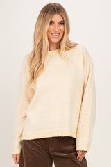 woman wearing a soft yellow striped oversized sweater with a relaxed fit and long sleeves