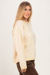 woman wearing a yellow and white striped oversized sweater and brown corduroy pants