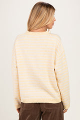 woman wearing a soft yellow and white striped oversized sweater, seen from the back, paired with brown corduroy pants