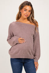 woman wearing a mauve off-the-shoulder maternity sweater and holding her baby bump