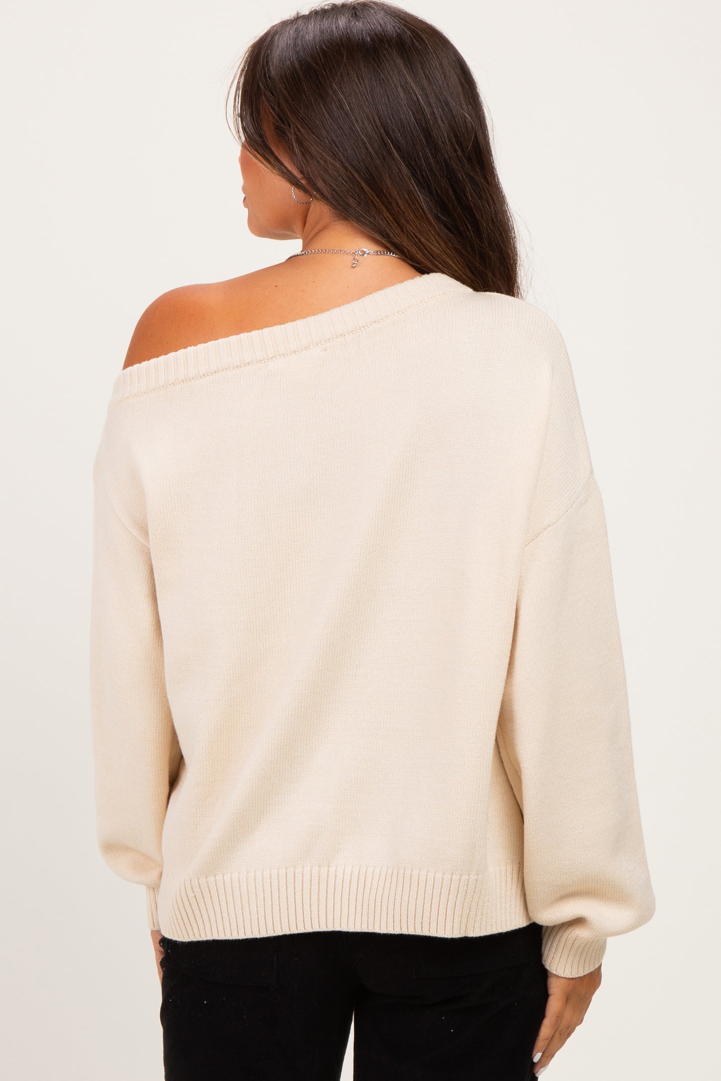 woman wearing a cream off-the-shoulder oversized maternity sweater