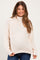 woman wearing a light beige maternity sweater with a high neckline and relaxed fit, showing her baby bump