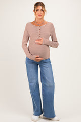 woman wearing a rust and cream striped maternity top and blue flared jeans, holding her baby bump