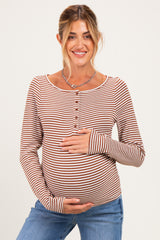 woman wearing a brown and white striped maternity top and holding her baby bump