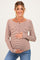 woman wearing a brown and white striped maternity top and holding her baby bump