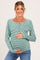 woman wearing a green and white striped maternity top with buttons, showcasing her baby bump