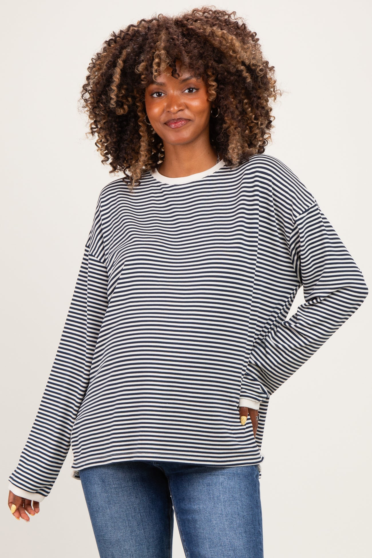 woman wearing a black and white striped long sleeve maternity top with a relaxed fit and a smile