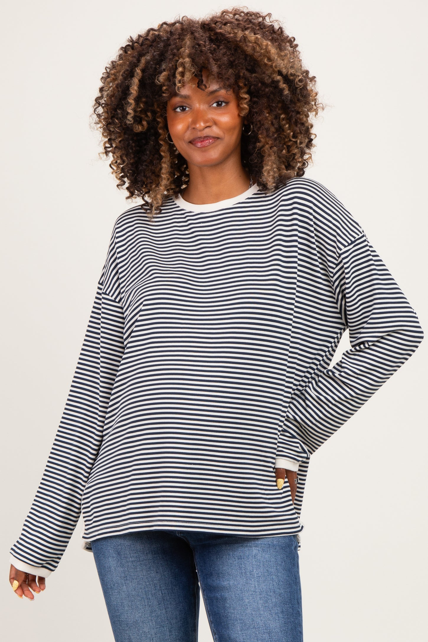 woman wearing a black and white striped long sleeve maternity top with a relaxed fit and a smile