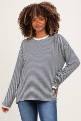 woman wearing a black and white striped long sleeve maternity top with a relaxed fit and a smile