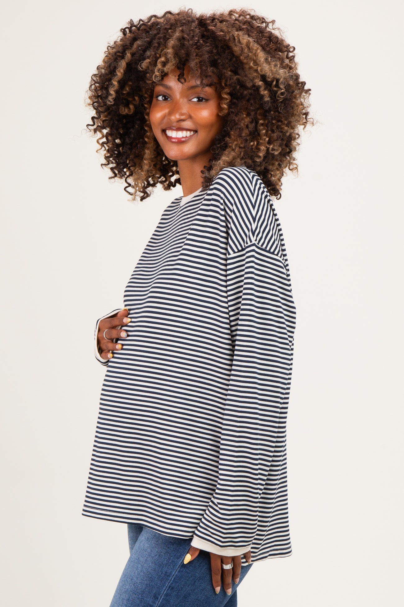 woman wearing a black and white striped maternity top and holding her baby bump