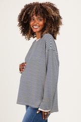 woman wearing a black and white striped maternity top and holding her baby bump