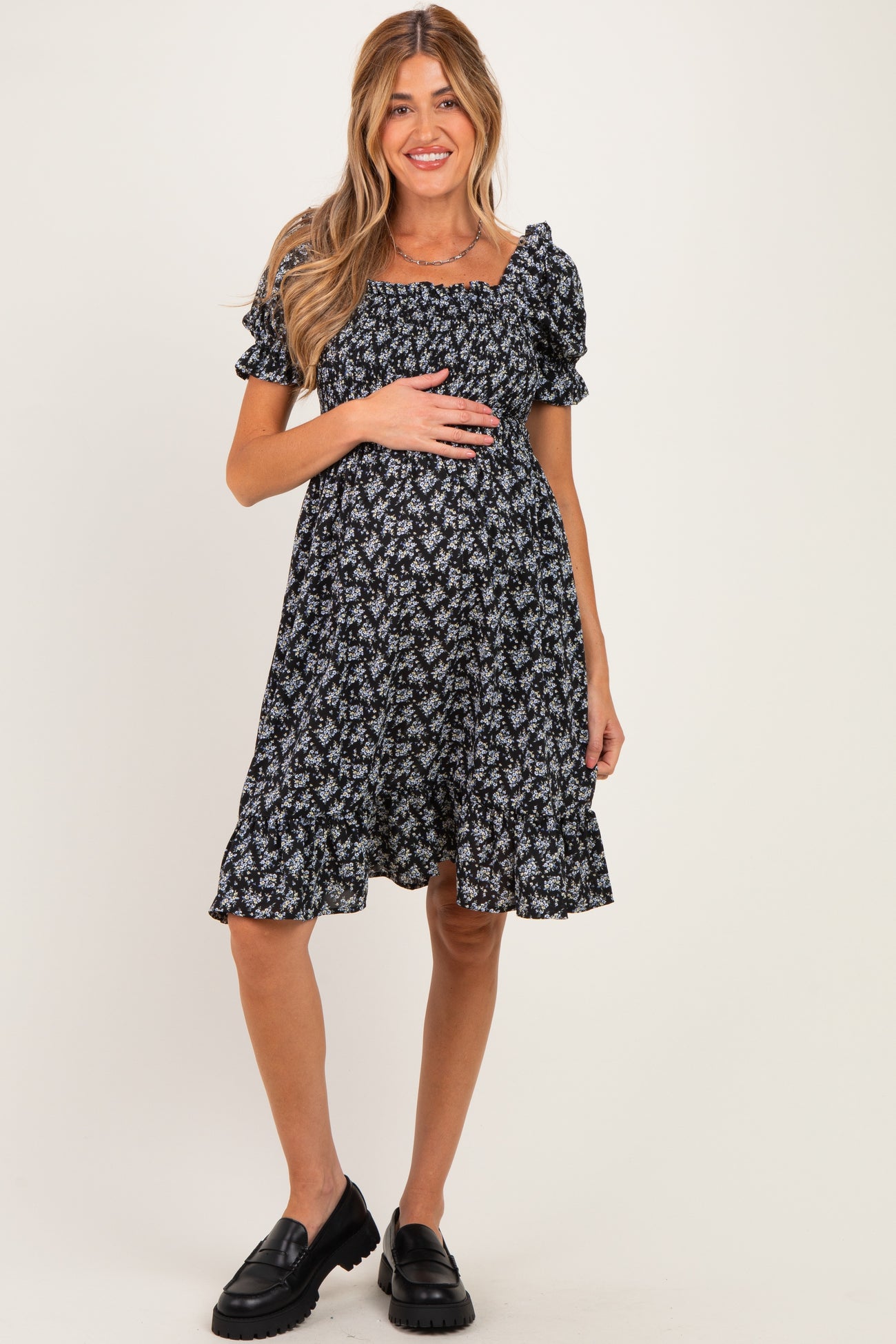 woman wearing a black floral maternity dress with puff sleeves and a fit-and-flare silhouette, showing her baby bump