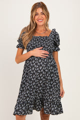 woman wearing a black floral maternity dress with puff sleeves and a baby bump visible