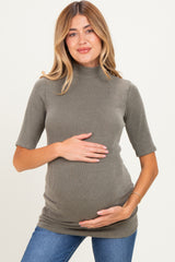 woman wearing a ribbed olive green maternity top and holding her baby bump