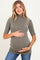 woman wearing a ribbed olive green maternity top and holding her baby bump