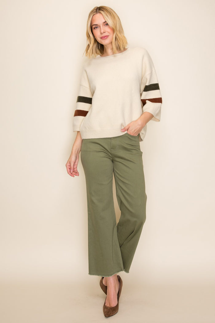 woman wearing a cream oversized sweater with striped sleeves and olive green wide-leg pants