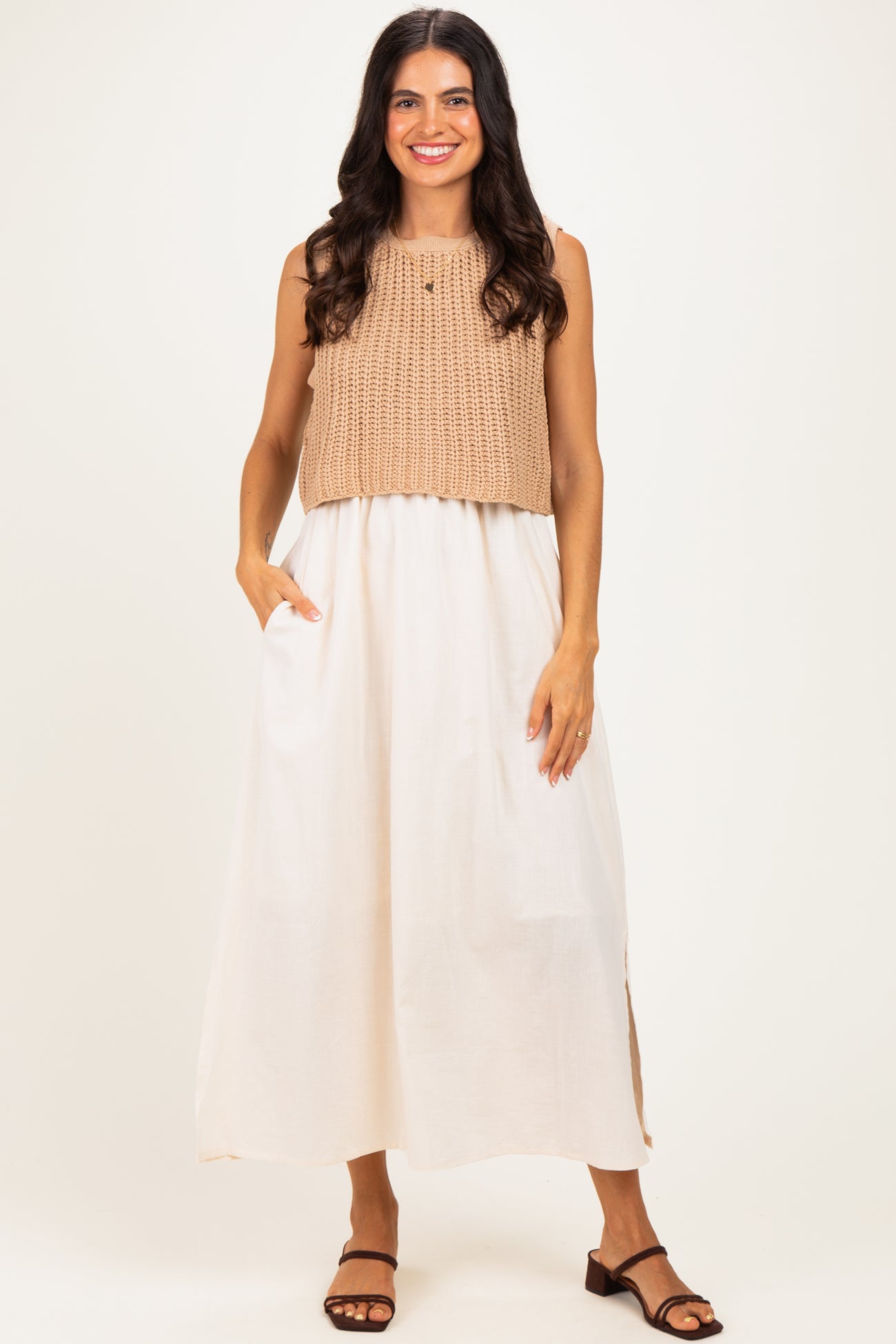 woman wearing a sleeveless beige knit top and a white maxi dress with side pockets