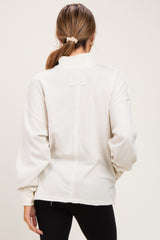 woman wearing a cream-colored maternity pullover with a high neckline and relaxed fit, showing the back view