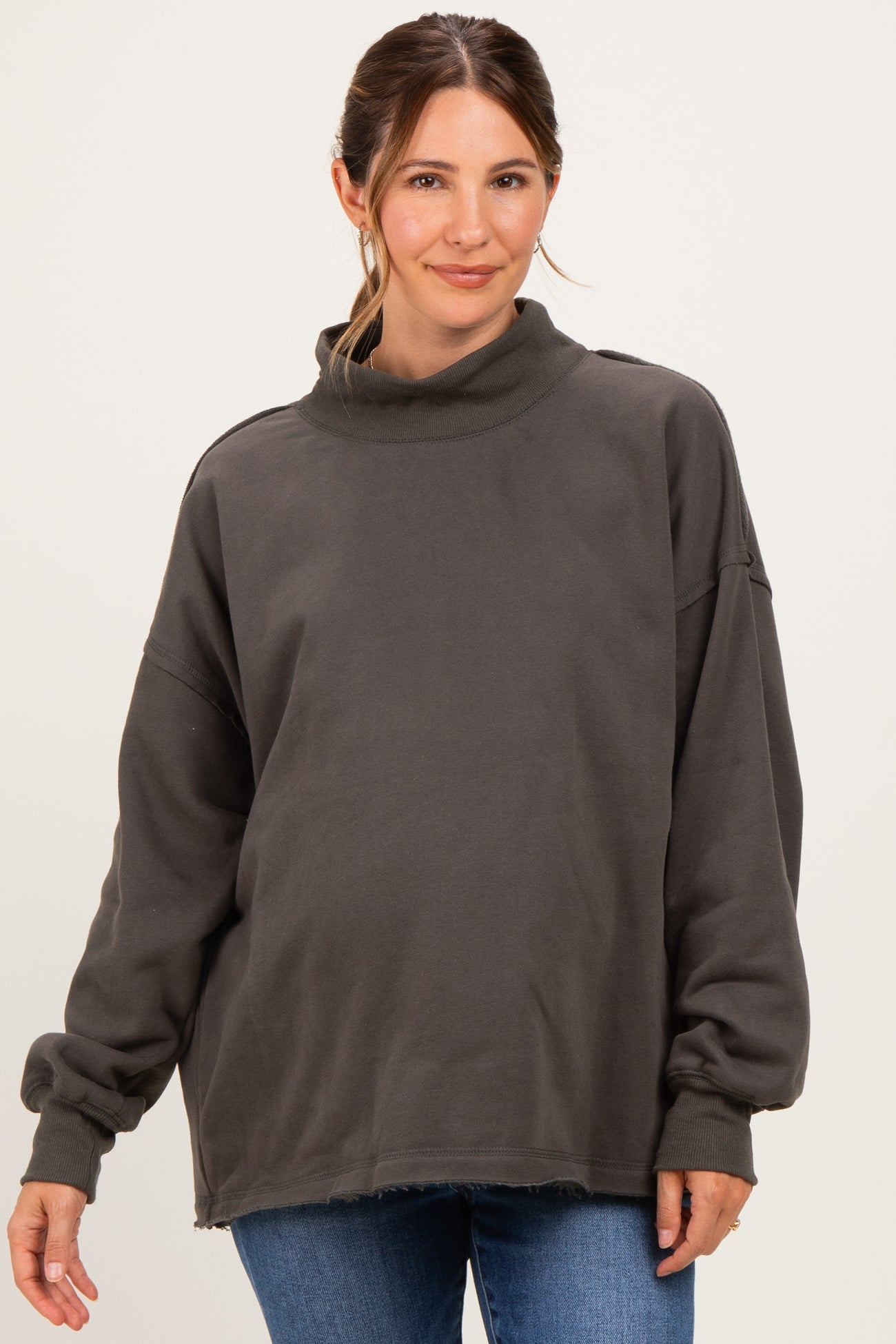 woman wearing a gray oversized maternity sweatshirt with a turtleneck and relaxed fit, showing a baby bump