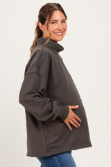 woman wearing a charcoal gray oversized maternity sweatshirt and holding her baby bump