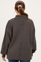woman wearing a dark gray oversized maternity sweatshirt with a high collar and seam detail on the back
