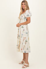 woman wearing a beige floral puff sleeve midi dress and beige heels, standing sideways against a neutral background
