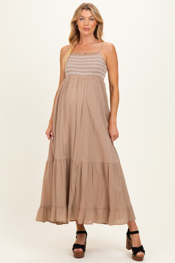 woman wearing a tan maxi maternity dress with a smocked bodice and tiered ruffle hem, showcasing her baby bump