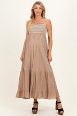 woman wearing a tan maxi maternity dress with a smocked bodice and tiered ruffle hem, showcasing her baby bump