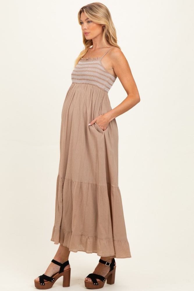 woman wearing a beige maternity maxi dress with a smocked bodice and pockets, showing her baby bump