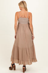 woman wearing a beige maternity maxi dress with a smocked bodice and tiered skirt, showing off her baby bump from the back
