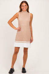 woman wearing a beige ribbed sleeveless dress with a pleated white hem and black chunky shoes