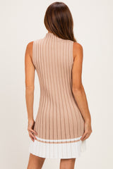 woman wearing a beige ribbed sleeveless sweater dress with a flared white pleated hem