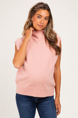 woman wearing a light pink sleeveless maternity sweater with a mock neck and baby bump visible