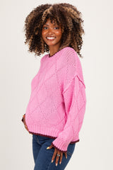 woman wearing a bright pink knitted maternity sweater with a loose fit and a visible baby bump
