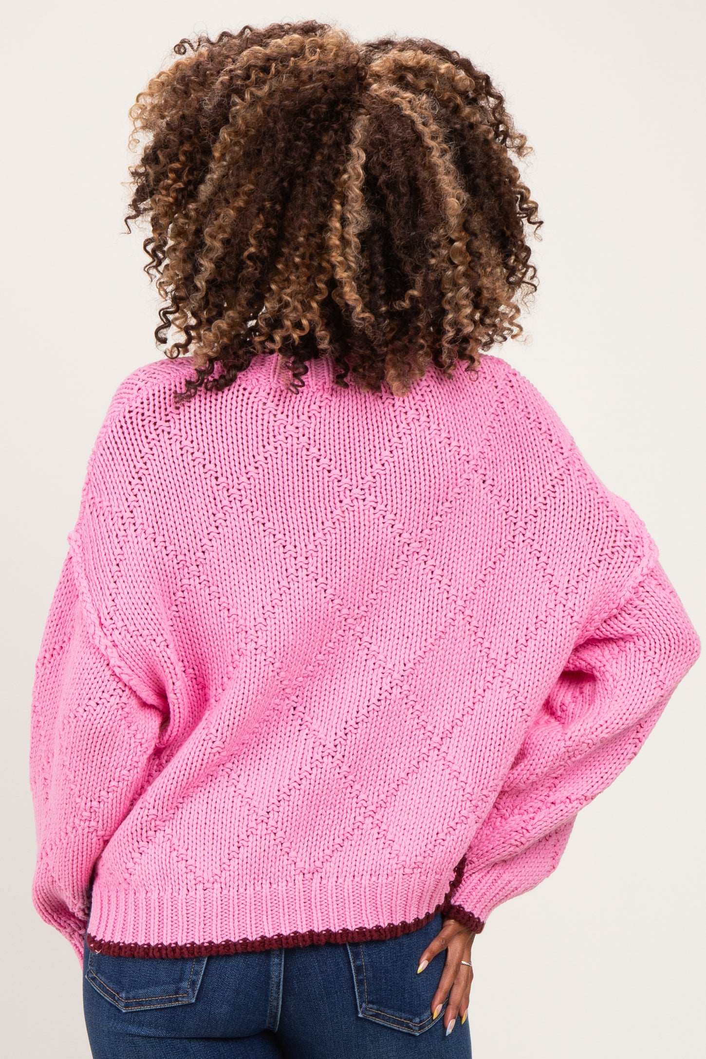 woman wearing a pink oversized maternity sweater with a textured knit design and long sleeves