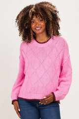 woman wearing a bright pink maternity wear sweater with textured diamond pattern and contrasting dark cuffs