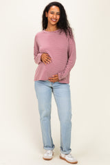 woman wearing a pink and white striped maternity top and holding her baby bump, paired with light blue jeans