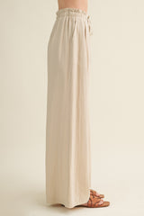 woman wearing high-waisted beige wide-leg trousers with an elastic waistband and drawstring detail