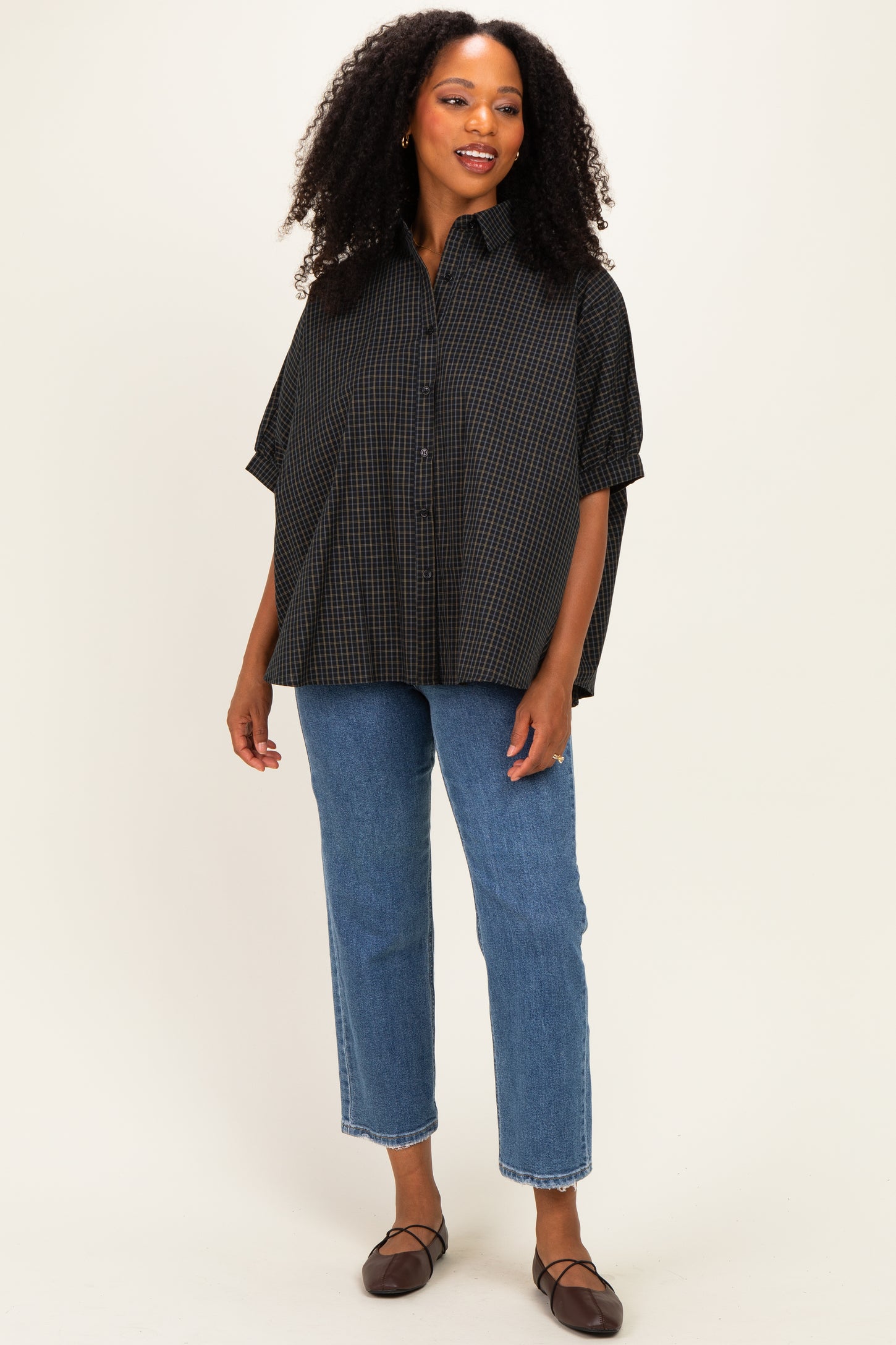 woman wearing a black and white checkered oversized button-up shirt with denim straight-leg jeans