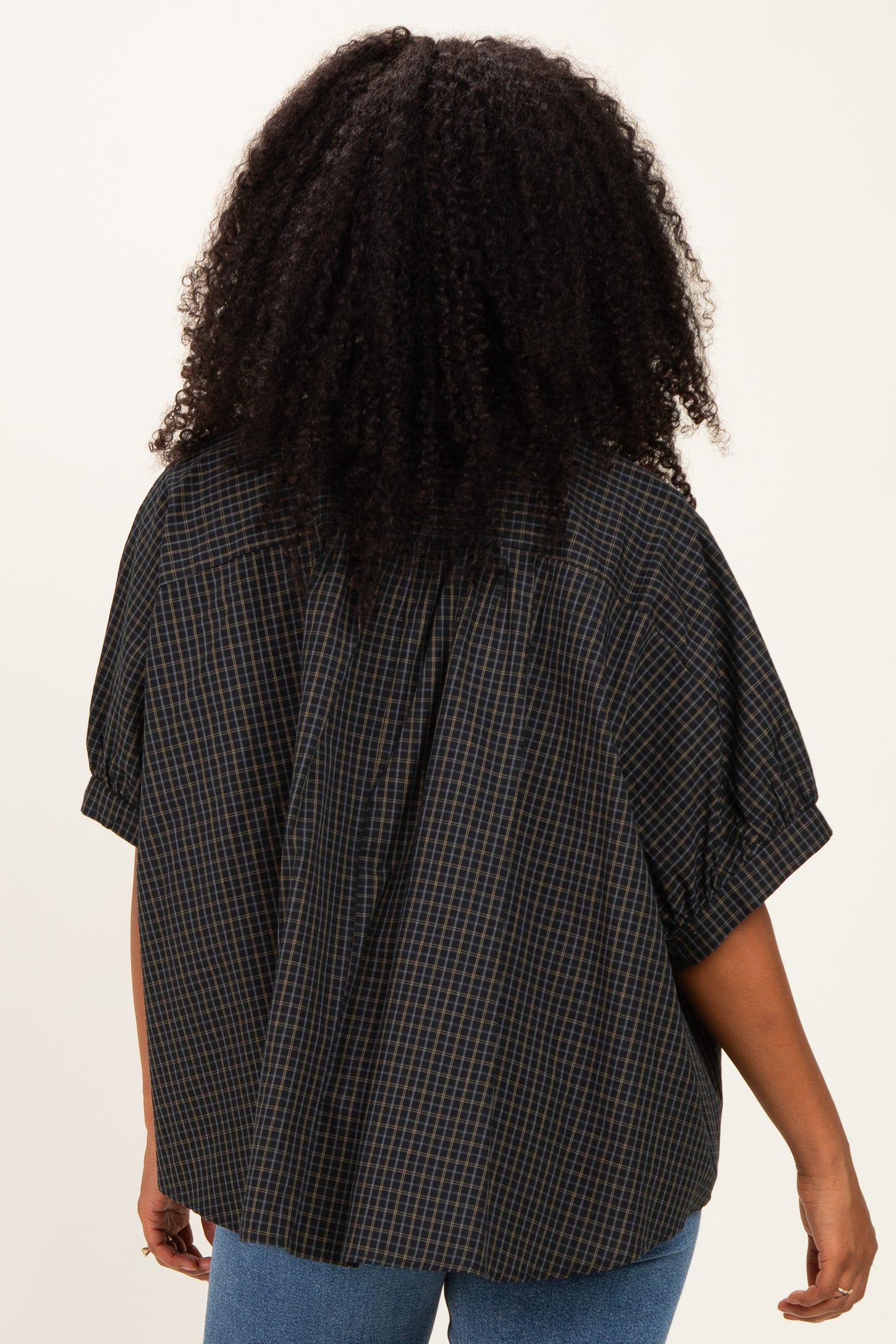 woman wearing a loose-fitting checked shirt in dark tones, shown from the back