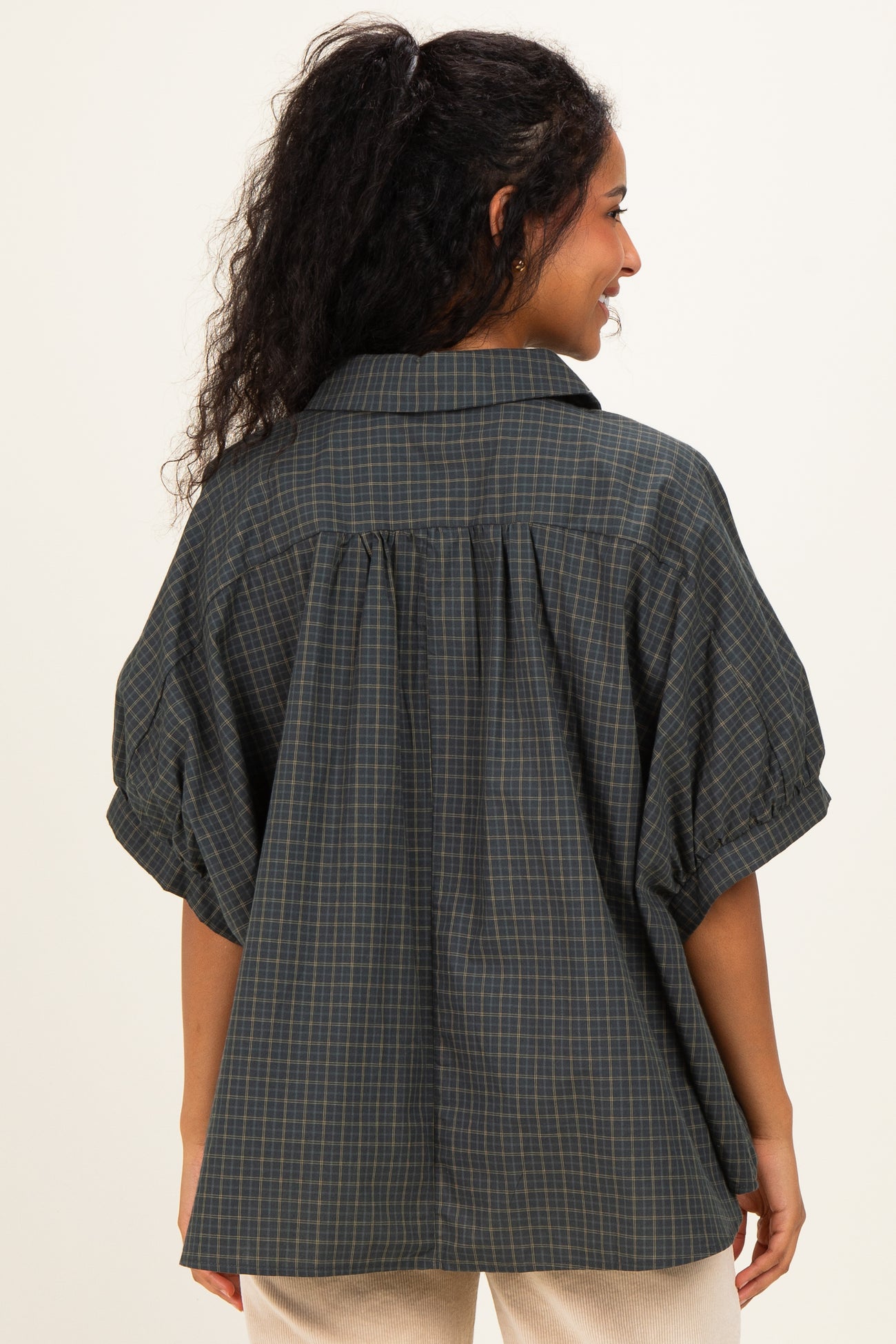 woman wearing a dark green checkered maternity shirt with puff sleeves and a relaxed fit, showing the back view