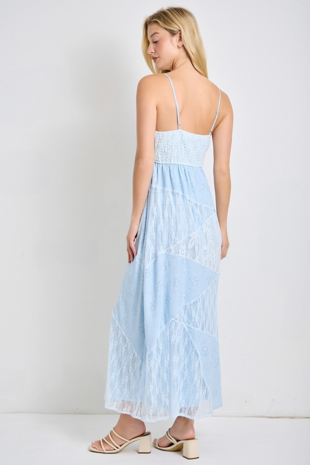 woman wearing a light blue maxi dress with lace detailing and adjustable straps, viewed from the back