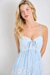 woman wearing a light blue lace sundress with adjustable spaghetti straps and a tie detail at the bust