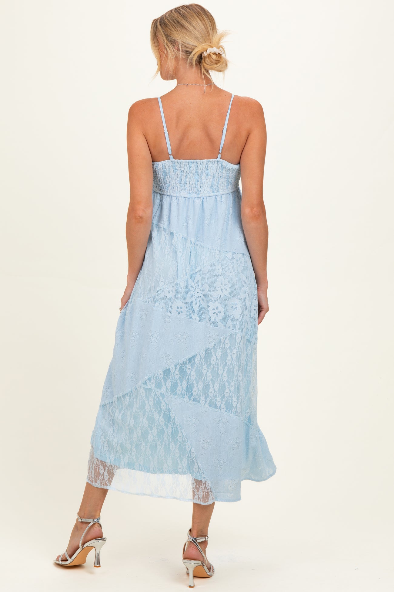 woman wearing a light blue lace maternity dress with adjustable straps and a flowy hem, showing off her baby bump