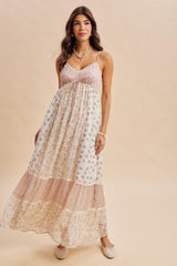 woman wearing a flowy floral maxi dress with spaghetti straps and tiered design in pastel colors
